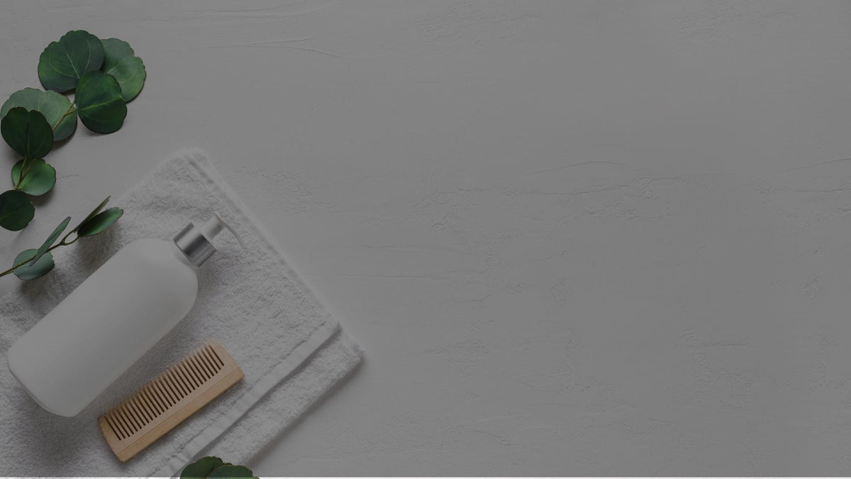 A white towel, Loxxie Hair shampoo bottle, and a brush arranged on a clean white surface.