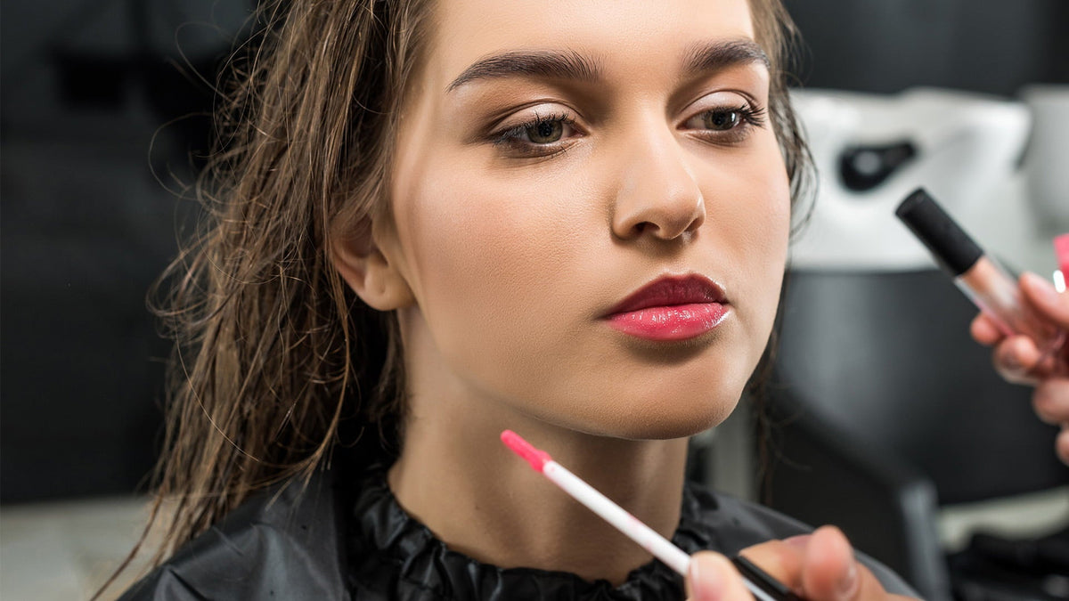 A woman receives makeup application from a professional artist at Loxxie Hair studio.