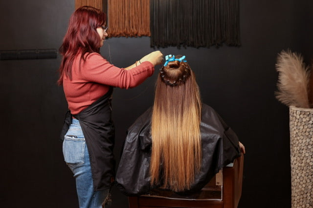 Hairdresser styling a client's hair in a salon setting.